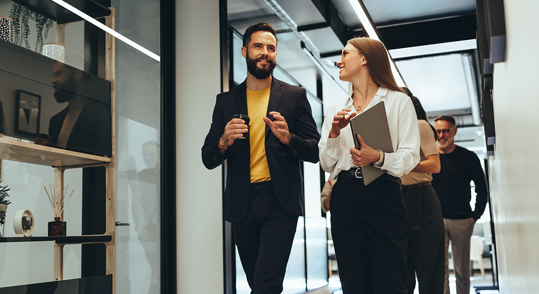 Coworkers chatting while walking in office hall