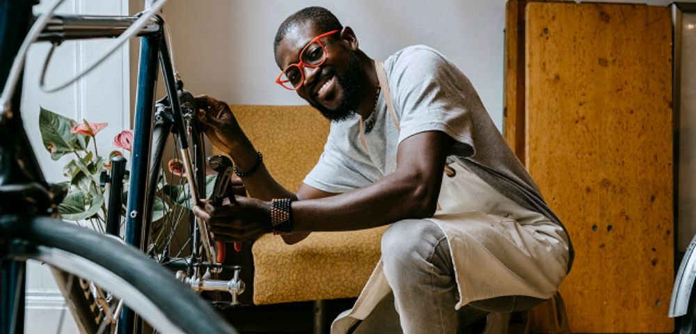 Man smiling while repairing a bicycle.
