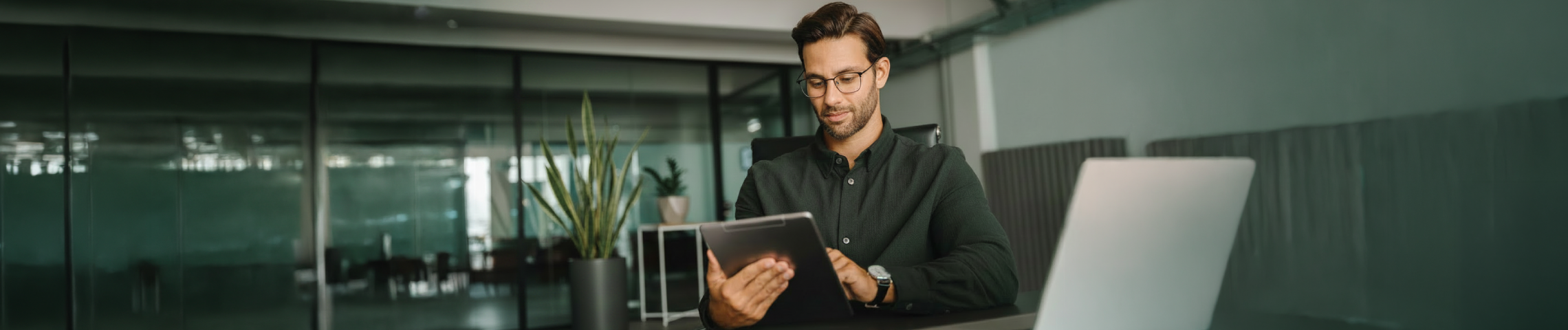 Man in glasses reading tablet at desk