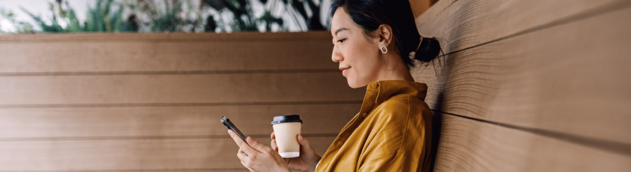 Person using mobile phone holding coffee