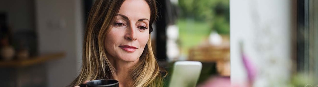 A woman drinking coffee looking on her phone