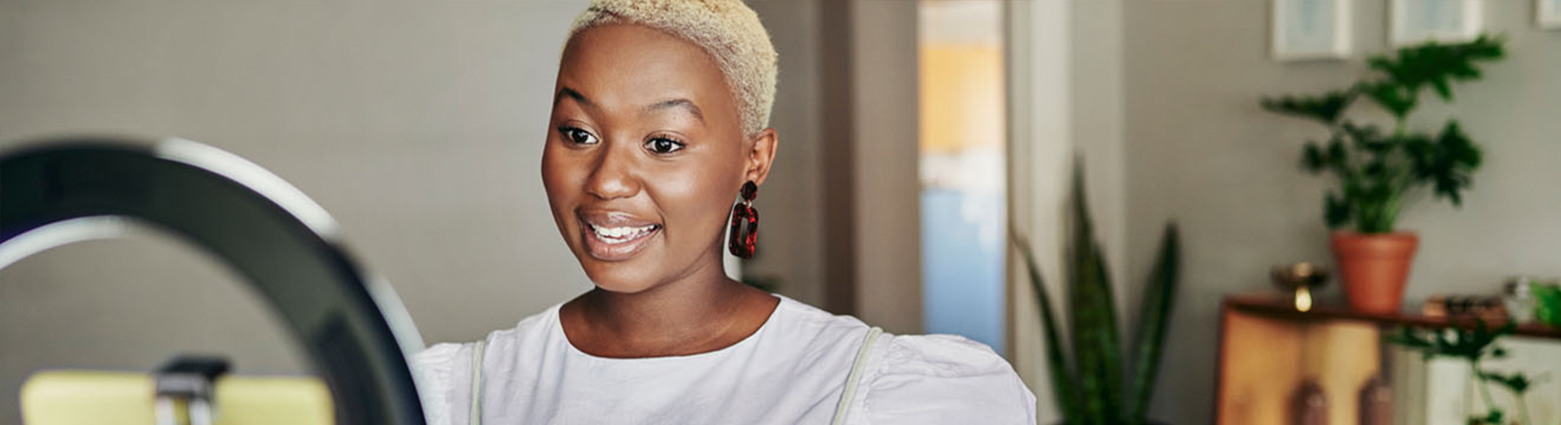 Woman recording a video using a smartphone and ring light at home