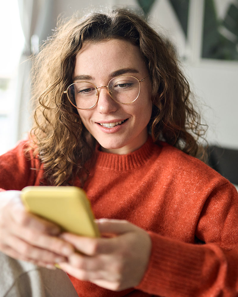 Women in orange sweater looking at mobile phone