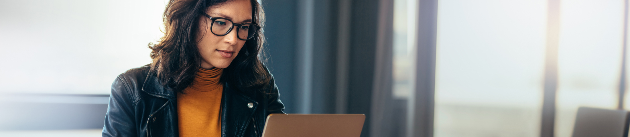 Woman with glasses using laptop indoors