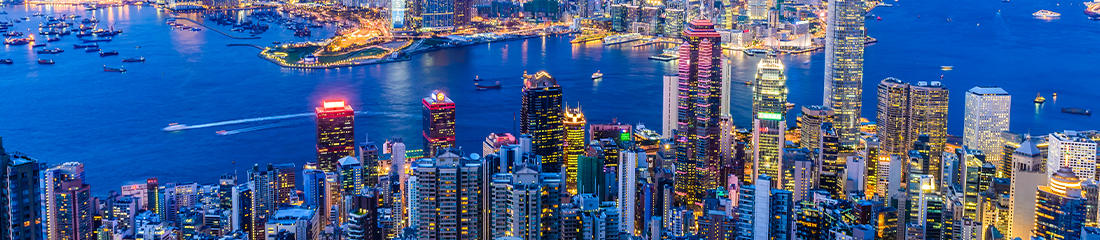 Aerial view of a brightly lit city skyline at night overlooking a harbour.