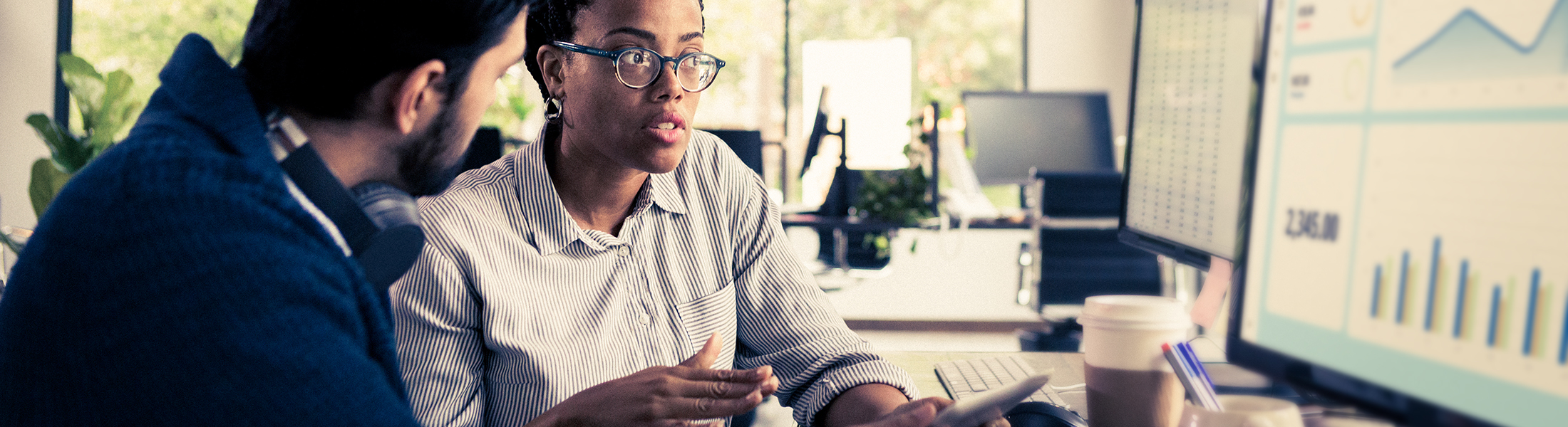 Coworkers discuss data at computer screen