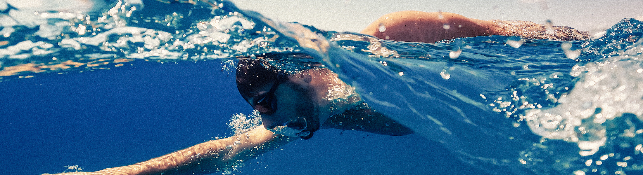 Swimmer wearing goggles glides through blue water