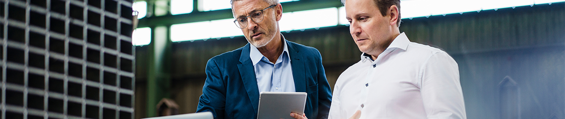 Two businessmen reviewing a tablet in an office