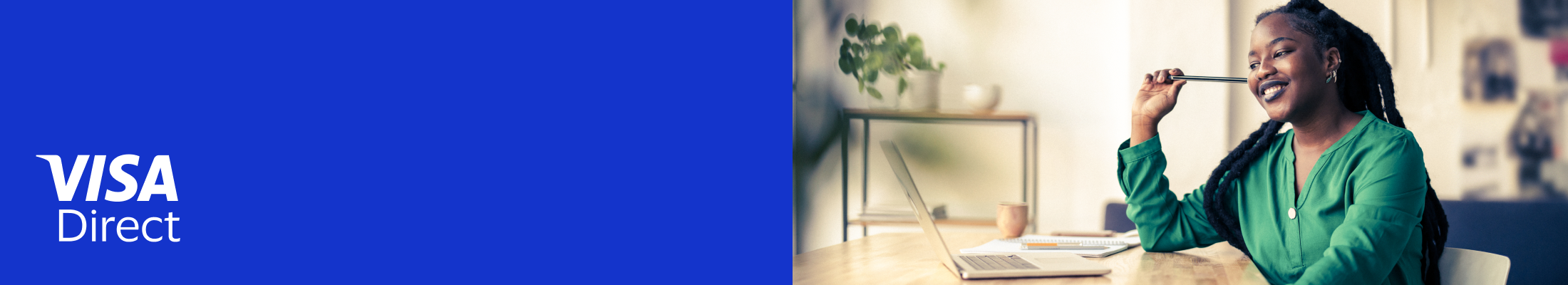 Woman smiling while working on laptop at desk.