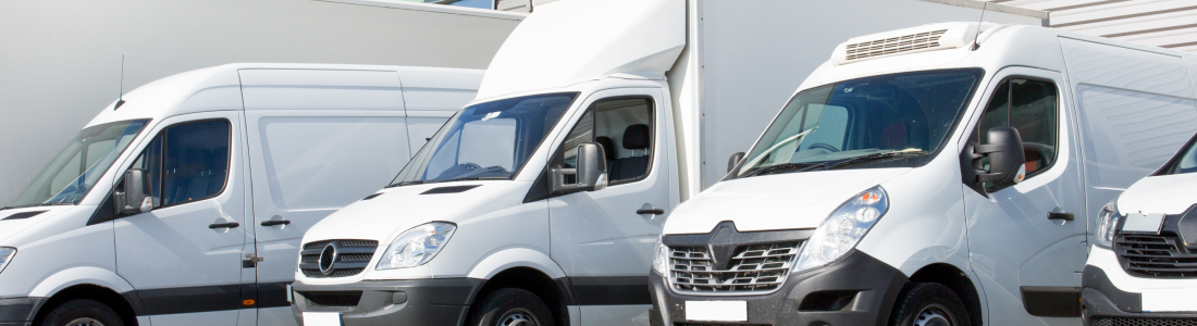 Row of white cargo vans parked outside